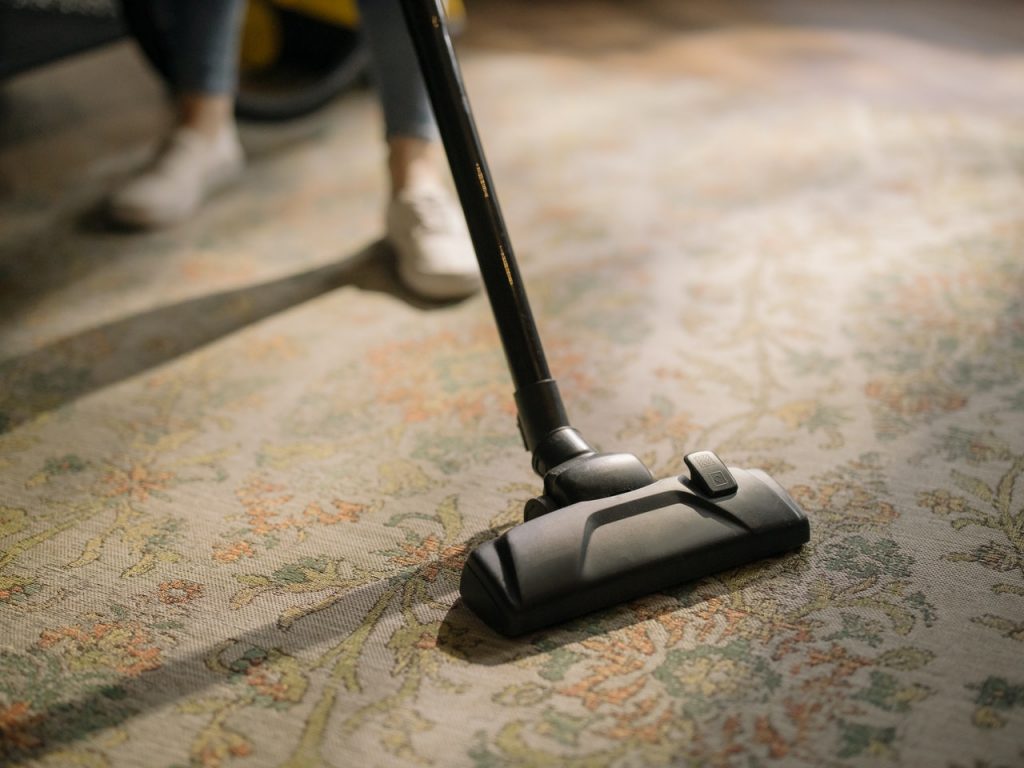 personne qui passe l'aspirateur sur un tapis