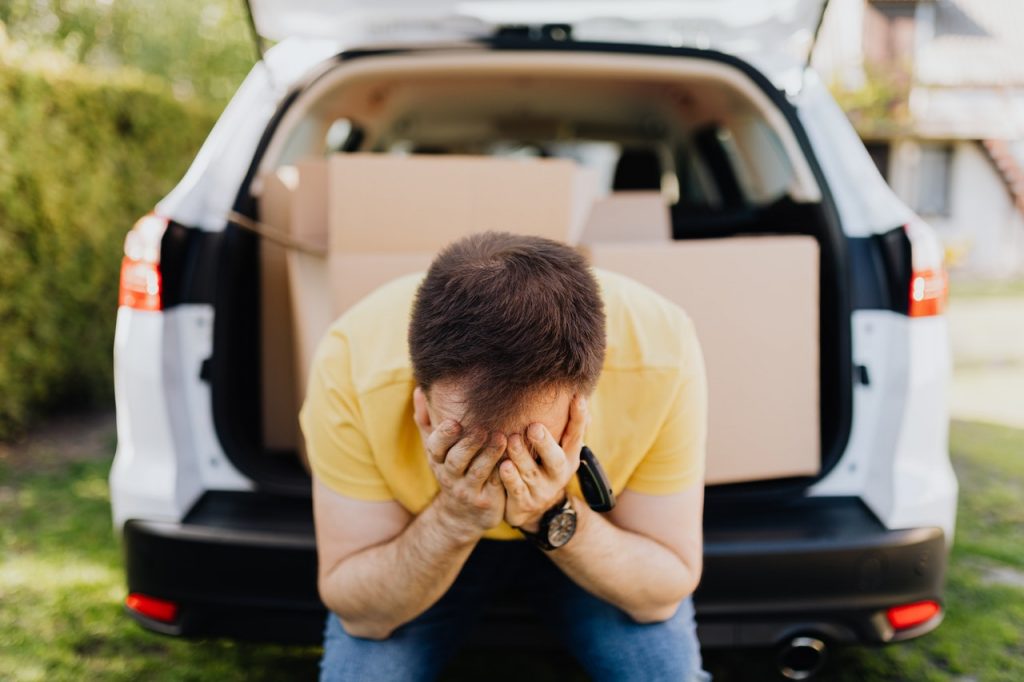 homme assis à l'arrière d'une camionette qui se tient la tête dans les mains